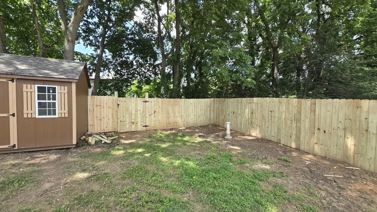 Pressure-treated wood privacy fence built around a backyard shed in Maryland